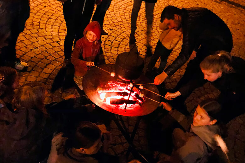 Erwachsene und Kinder um eine Feuerschale am Marshmallow braten